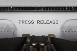 Typing text PRESS RELEASE on vintage manual typewriter. Close up of writes word on white paper. Shot in macro.