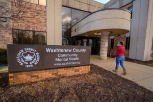 Woman walking by Washtenaw County Community Mental Health Sign