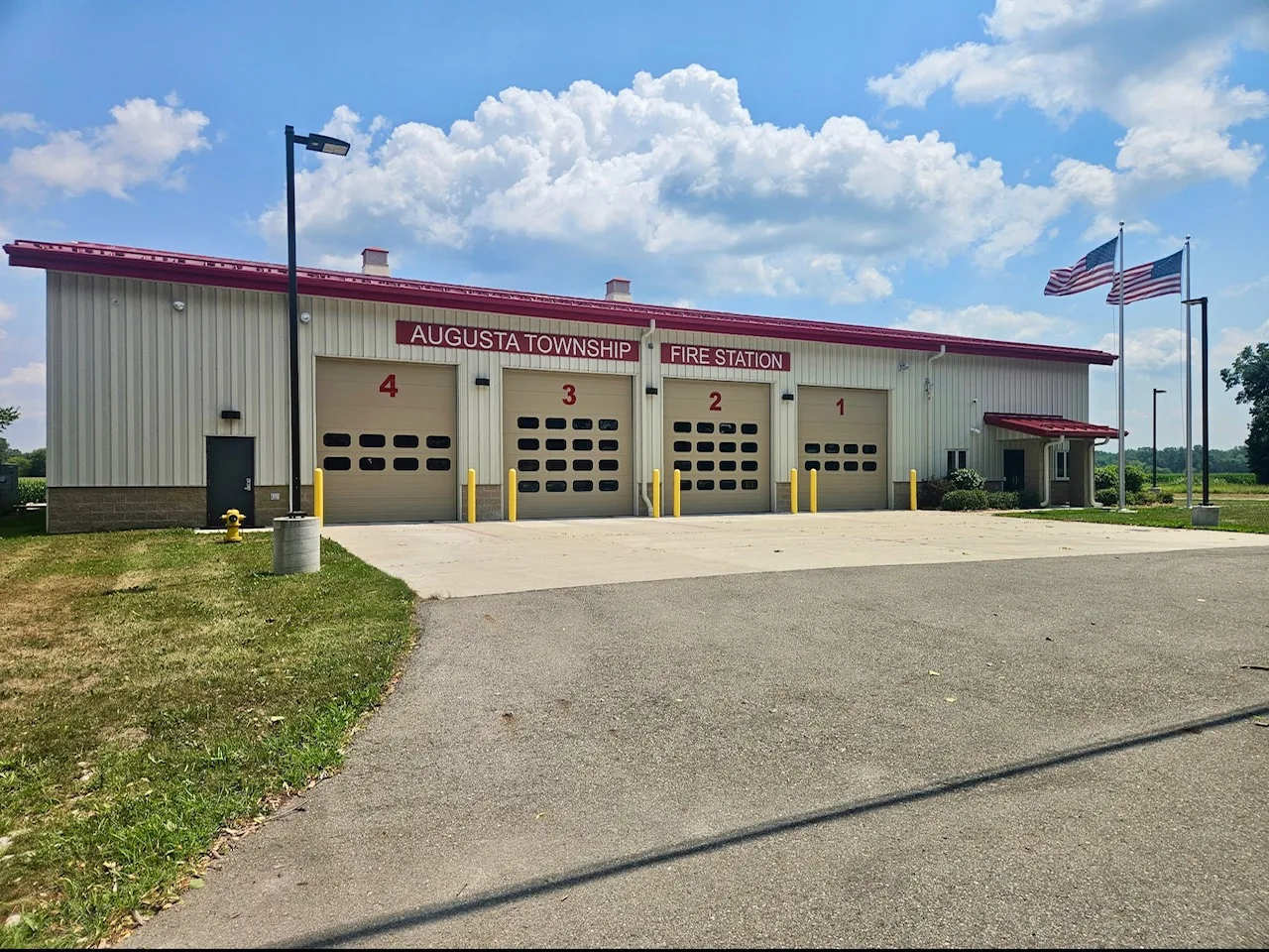 The Augusta Township Fire Station, a tan building with four garage bays and two American flags flying outside.